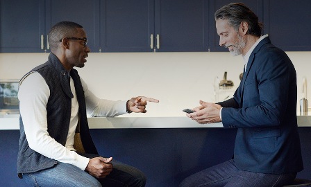Two males sit on benches in a blue kitchen setting