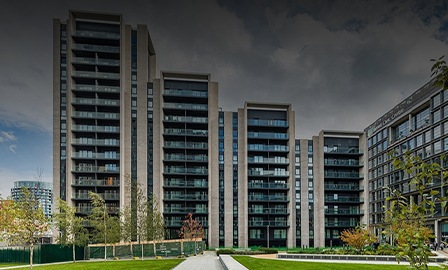 A block of residential flats are shown with a garden in front of them