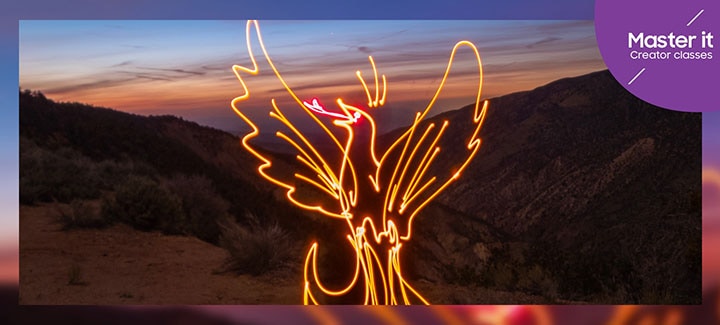 A man at sunrise makes a light painting of a rising phoenix in the air. Master it. Creator classes.