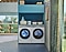 A white washer and dryer set is in a bright laundry room with light blue cabinets.