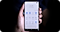 A hand holding Samsung smartphone showing application icons on screen