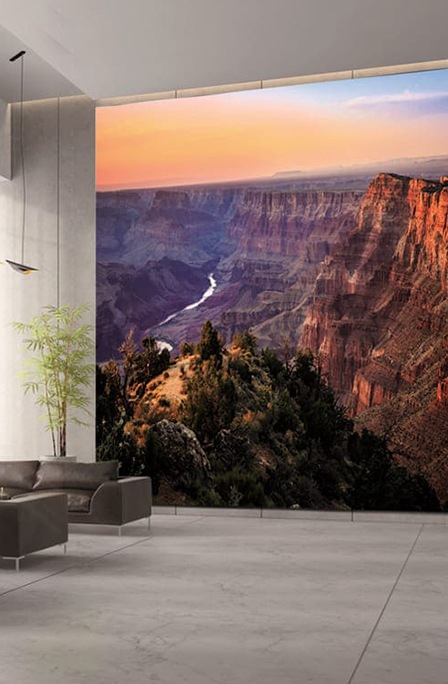 The Wall screen, showing the red valley scenery, on display in a corporate lobby with sofas near wide windows on the left and the front desk on the right.