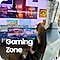 A female sits on a gaming chair with her back to the camera. In front of her are multiple screens with gaming graphics on display