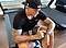 A man wearing a colorful graphic t-shirt stands in a kitchen with white cabinets and stone countertops. He stands at the kitchen island with his hands on the counter. There is a laptop open on the counter in front of him. He says to the camera, "What's up, guys? I'm Dustin Poirier and I'm excited to join Team Galaxy because I've been using Samsung products for years. I use these in my everyday life, so it only makes sense to join the team."