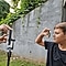 A behind-the-scenes visual of a boy being photographed through a slinky using Galaxy S21 Ultra 5G. He is holding one end of the slinky up to his face, while the photographer is holding the other end to the camera lens.