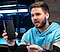 Video creator, Caleb Natale,wears a blue, gray and black hoodie pullover. He holds a Galaxy S22 Ultra in his right hand and a black S Pen in his left.