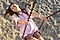 A woman in a t-shirt and shorts rides a swing on a sandy beach.