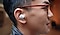 A profile shot of a man wearing a white Galaxy Buds+ earbud in his right ear