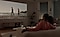 A couple sits on a couch watching a video being projected onto the wall by The Freestyle projector.