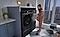 A woman wearing pajamas loads a blanket into her Samsung Bespoke Ultra Capacity washer and dryer set.