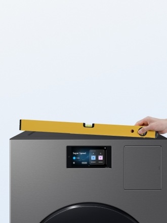 Hand holds a yellow level at an angle on top of Bespoke AI Laundry Combo™ in Dark Steel