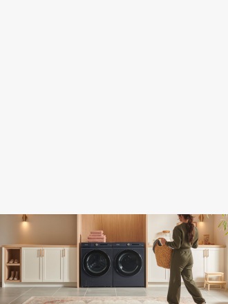 Person with laundry basket walking into laundry room with side-by-side washer and dryer