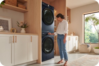 Woman using Samsung Navy stackable washer and dryer set in laundry room