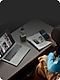 Top down view of person sitting at a desk with an open laptop and newspaper while looking at a smartphone