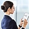 A professionally-attired woman uses a tablet in a professional setting.