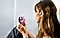 A side-profile view of a lady sitting, she has the Galaxy Buds Plus in her ear and is holding the Galaxy Z Flip phone in both hands in front of her