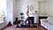 Cat Meffan in a Warrior I pose on a black yoga mat in a bright living room