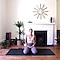 Cat Meffan sits, kneeling on a black yoga mat in her living room. Her knees are wide apart.