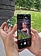 Hands holding a small mirror and a black Galaxy S21 Ultra 5G with the screen showing a girl looking to her left