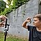 A behind-the-scenes visual of a boy being photographed through a slinky using the Galaxy S21 Ultra 5G. He is holding one end of the slinky up to his face, while the photographer is holding the other end to the camera lens.