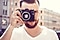 Мужчина держит фотокамеру на фоне городского пейзажа и готов сделать отпускные фотографии.