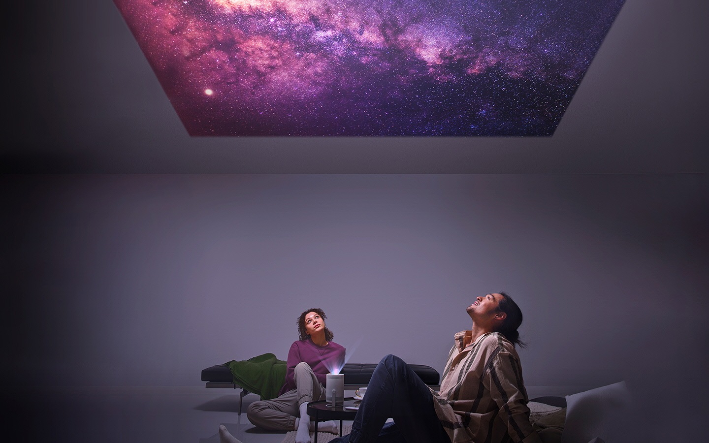 A man and woman stargaze at stars projected onto their ceiling from The Freestyle.