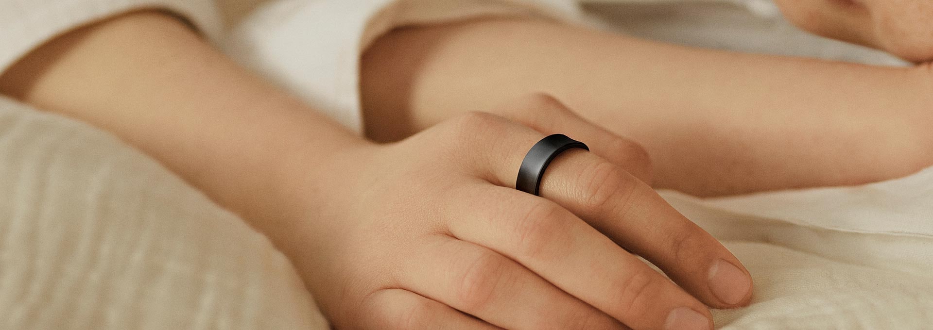 Một bàn tay đeo Galaxy Ring đang đặt trên giường.