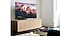 Bên trong một phòng khách được chiếu sáng rực rỡ, TV The Frame được đặt trên tủ TV bằng cách sử dụng tùy chọn chân đế studio và nhìn từ cận cảnh một bên. Hình ảnh dãy núi có thể nhìn thấy trên màn hình.