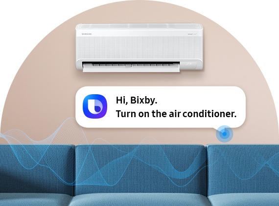 There’s a wall-mounted WindFree AC on a light pink wall, with a conversation bubble below it reading, “Hi Bixby. Turn on the air conditioner.” Below the bubble, blue lines represent sound waves from the voice command. A blue sofa sits beneath the AC.