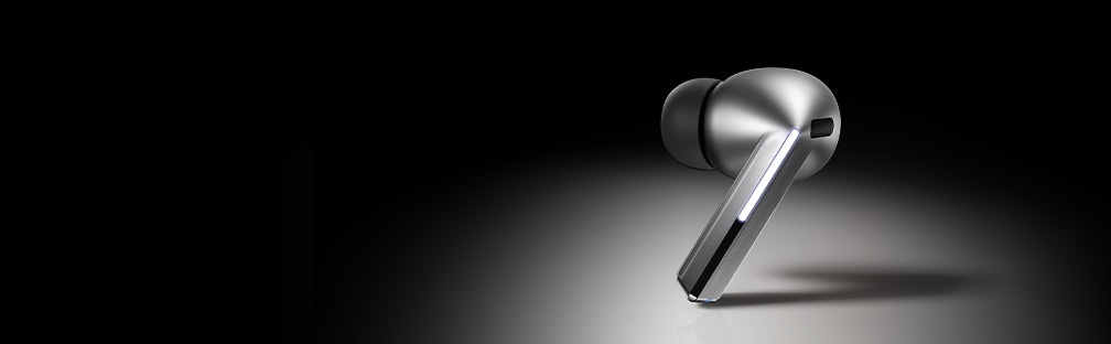 A pair of silver Galaxy Buds3 earbuds hovering above the open case that is tilted toward the left. The text 'Galaxy AI is here' with a Galaxy AI icon can be seen.