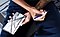 An overhead shot of a person with arms crossed over one's lap, holding a Galaxy Note10 in one hand and an S Pen in the other