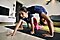 A young girl practices Wheel pose on her yoga mat as a younger girl crawls underneath her perpendicularly.