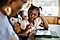 A young girl sitting at a table in front of a Galaxy Tab A7 as she is quizzed by an older woman.