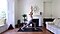 Cat Meffan in a Warrior I pose on a black yoga mat in a bright living room