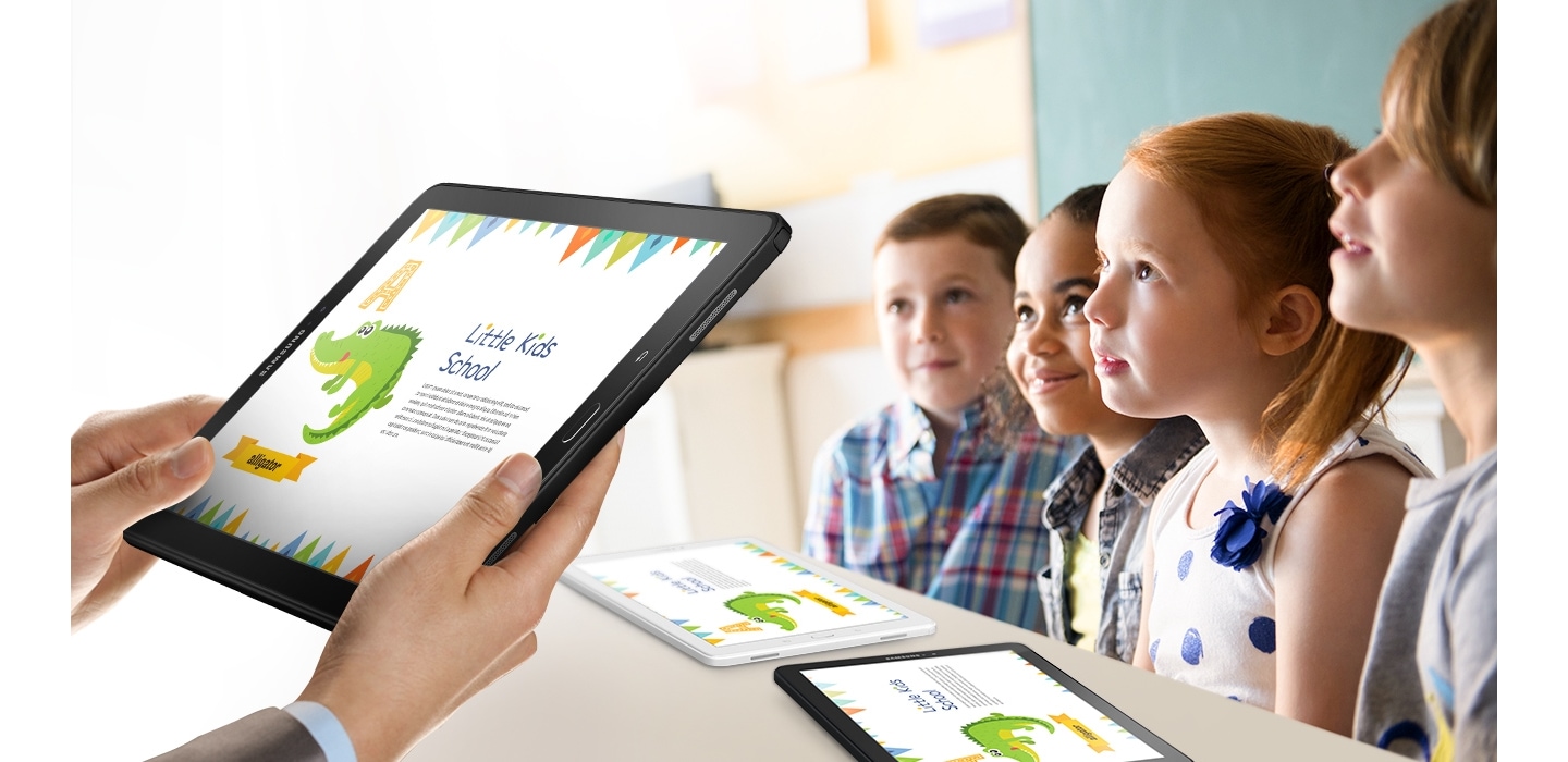 Mo segura o Galaxy Tab A com a imagem de um aplicativo escolar infantil. Ao lado, crianas prestando ateno e outros dois Galaxy Tab A sobre uma mesa com o mesmo aplicativo na tela