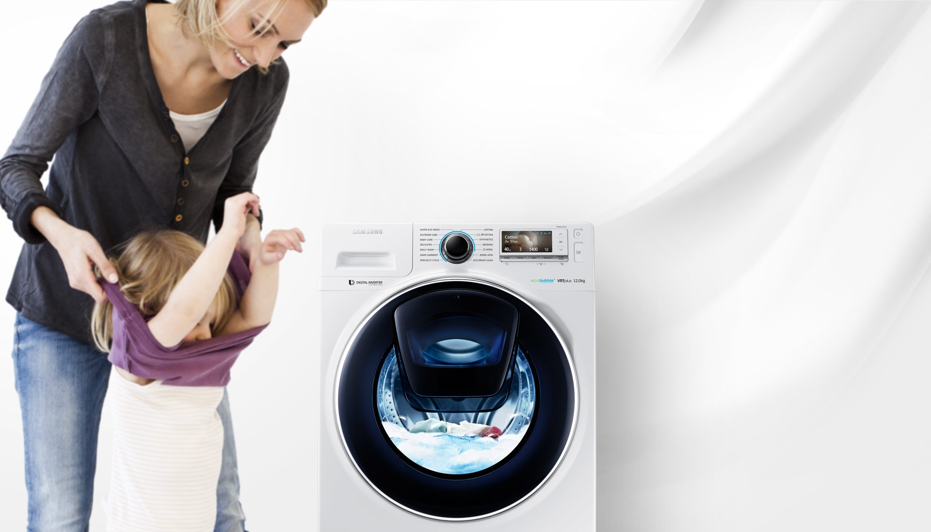 An image of a woman taking off her child's clothes next to a WW6500 washing machine which is in the middle of a cycle.