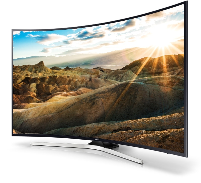 Jobboldali távoli szögből a Samsung UHD TV, egy sugárzóan fényes tájképpel a képernyőjén.