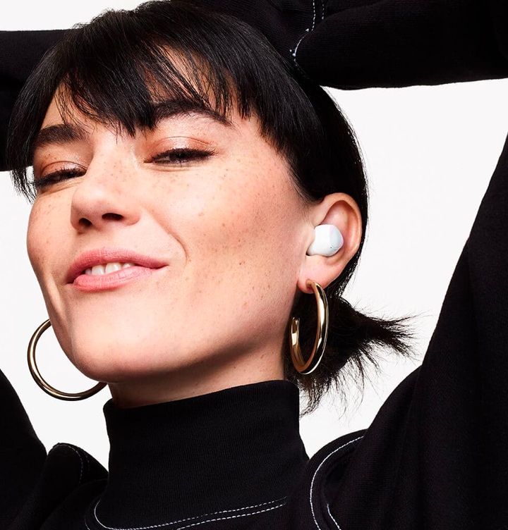 A woman holding her hands over her head, wearing Galaxy Buds plus in white