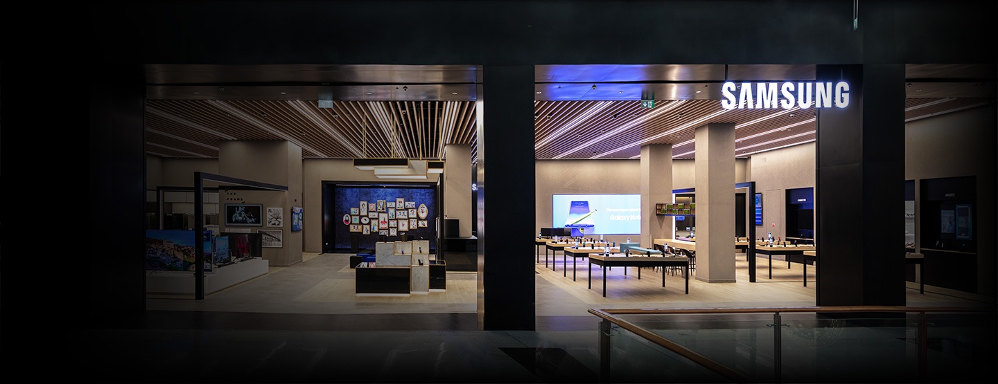 A large LED display is lit up to mimic an urban backdrop in line with the theme of Samsung City with the words "We are with you everyday" featured prominently in the center. The floor below the display is lit up with lights in shades of blue and yellow.