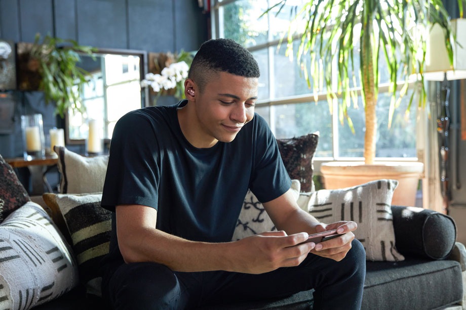 Twitch streamer Myth sits at home playing mobile games on his Galaxy Note20 with Galaxy Buds Live in his ears.