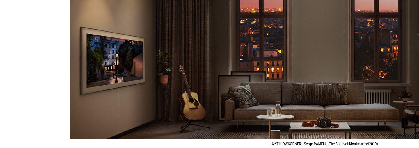 The Frame on Art Mode displays the picture, ‘The Stairs of Montmartre (2010)’ by Serge Ramelli in a dimly lit living room. The romantically lit city is visible from the windows. Copyright Yellowkorner.