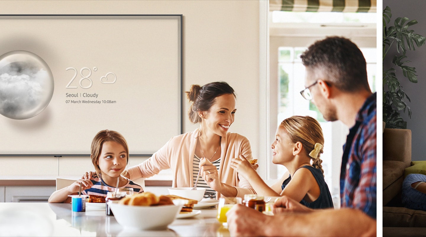 A family of four have gathered for breakfast, and a Super Big TV in Ambient Mode displays the weather forecast and date: "28 degrees Celsius, Seoul, cloudy. 7 March Wednesday 10:08 am."