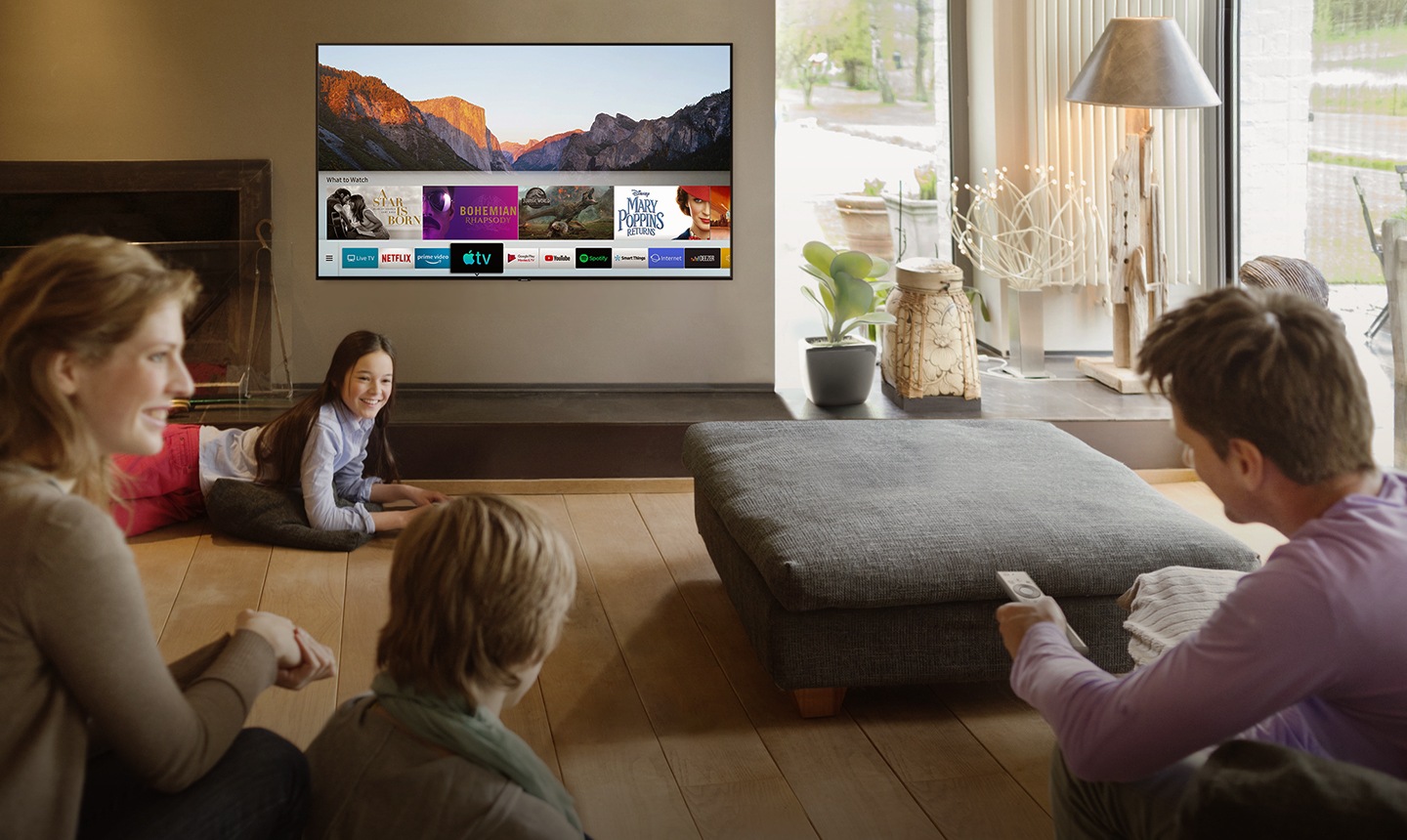 People are watching Smart TV in the living room and Smart Hub UI is displayed over a nature background image on TV screen