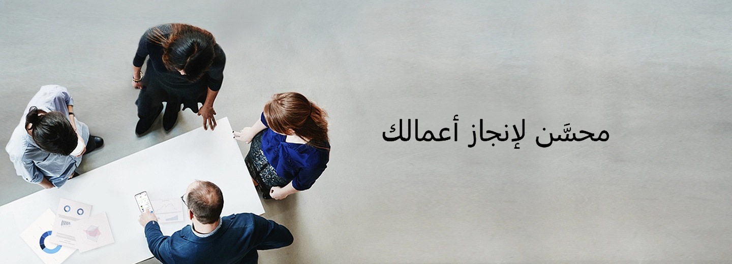 أربعة أشخاص واقفون حول طاولة تعلوها الرسومات التخطيطية، ويوجد رجل يشير إلى شاشة هاتف Galaxy S20 Ultra، وبجانب الصورة النص “محسَّن لأغراض العمل”
