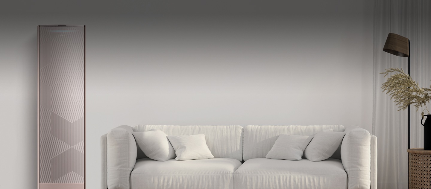 A living room with a white sofa at the center, a lamp and a plant on the right and a smart airconditioner on the left.