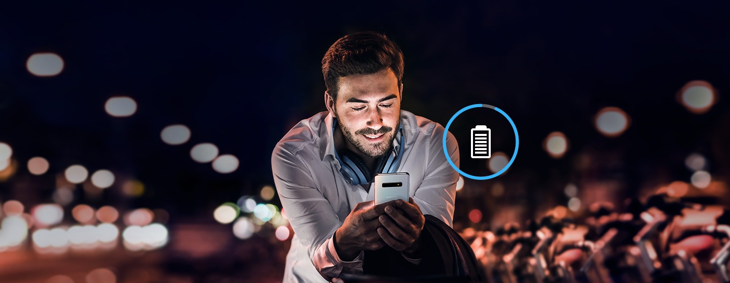 Image of man working at night on Galaxy S10 plus with overlaid battery icon.