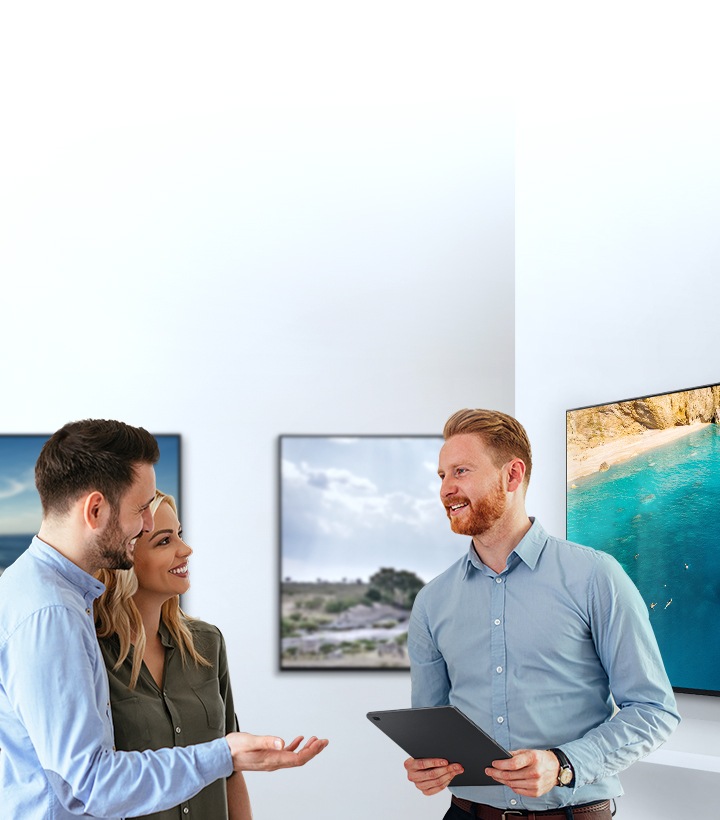For buying a new TV, a man and woman are talking with a male sales representative about TV features in a TV show room.