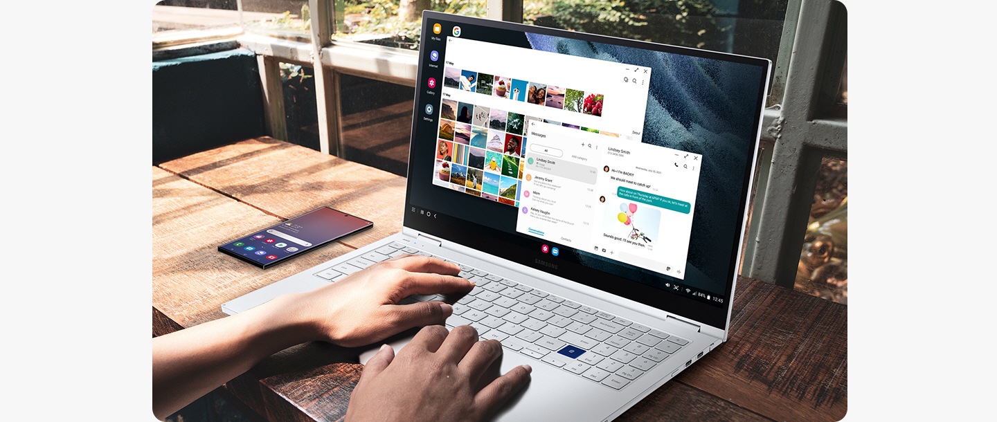 Një kompjuter portativ Samsung është duke u përdorur. Pranë kompjuterit portativ është një pajisje smartfon Galaxy duke treguar ekranin fillestar. Me Dex, përdoruesi është duke përdorur ekranin e kompjuterit portativ për të parë galerinë ndërsa gjithashtu dërgon mesazhe me tekst.