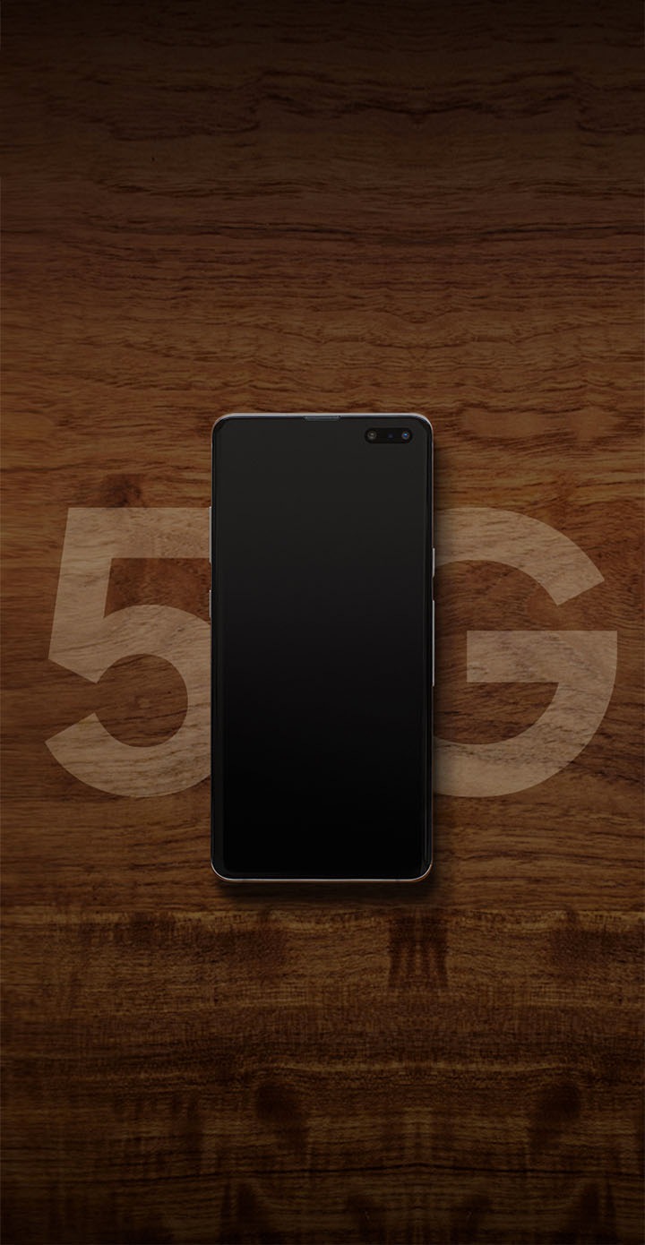 5G djegur në tryezë kafe prej druri, telefoni 5G në qendër ndërmjet ‘5’ dhe ‘G’.