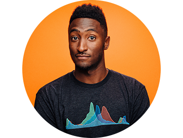 Primer plano de Marques Brownlee sobre un fondo naranja. Lleva una camiseta y sonríe ligeramente con las cejas levantadas.